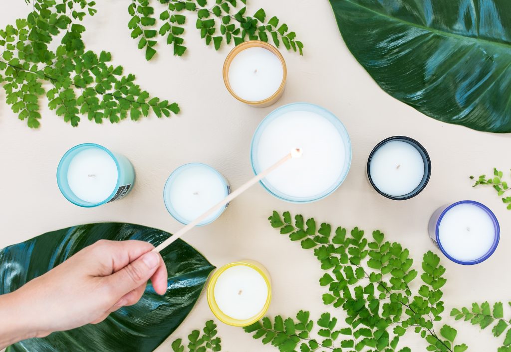 Plusieurs bougies sur une table blanche avec de la verdure