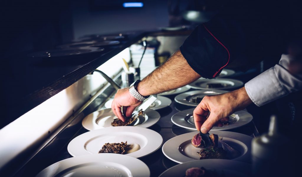 Cuisinier qui dresse des assiettes en cuisine